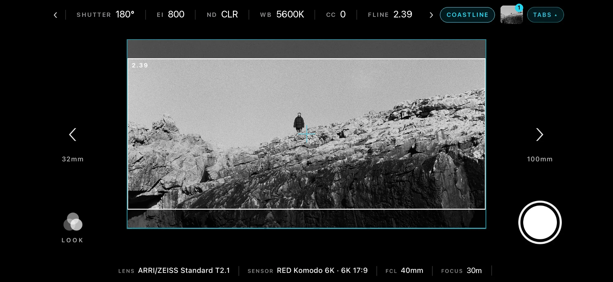 Viewfinder framing a lone walker on a black-and-white sea cliff at 2.39, with camera settings across the top and the lens and sensor below